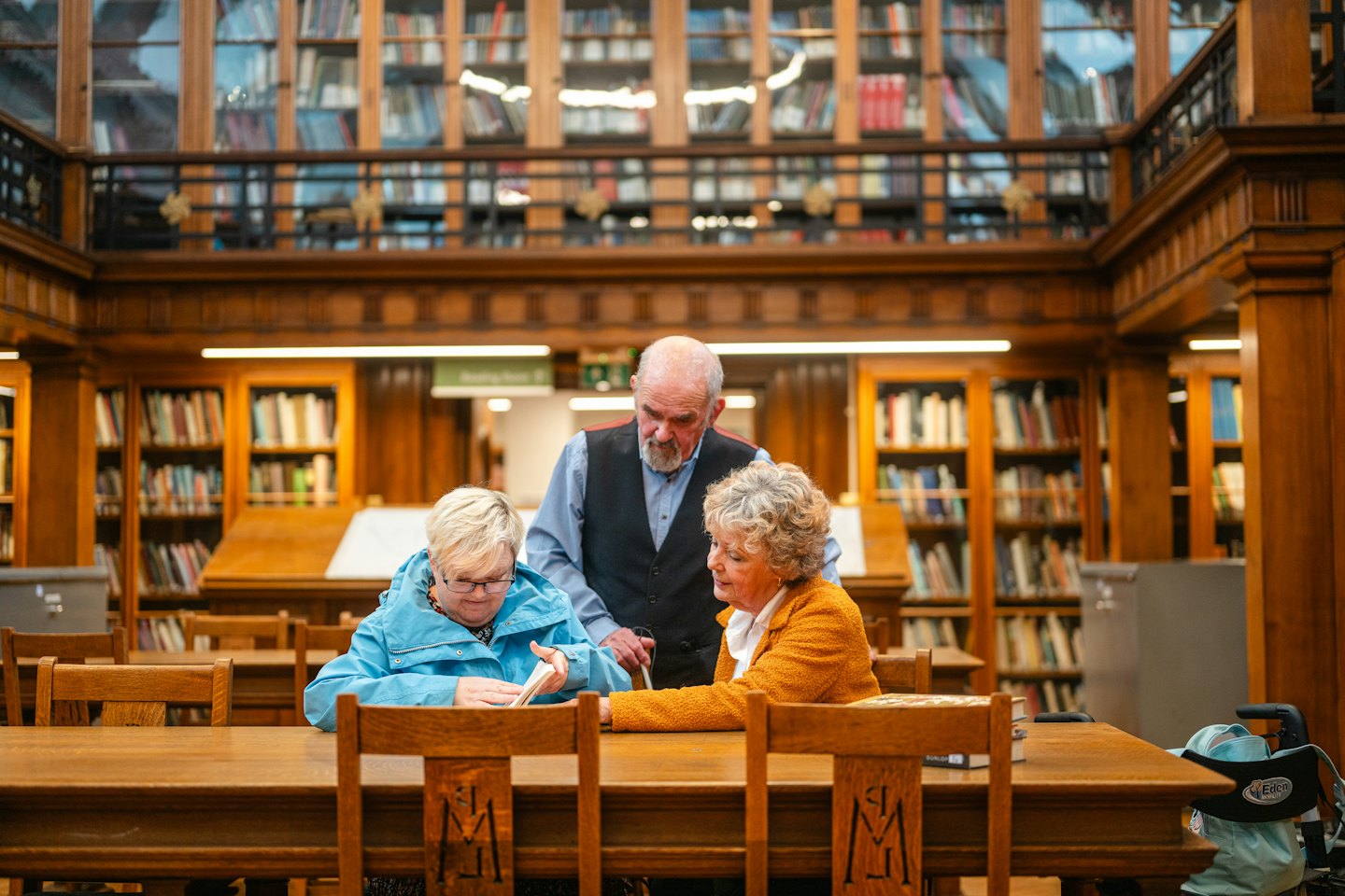 Trzy osoby omawiają dokument przy stole w bibliotece.